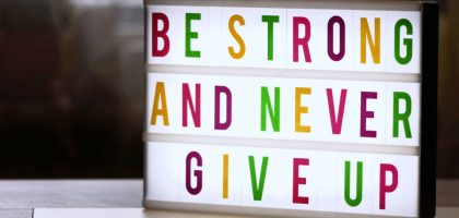 Motivational lightbox sign displaying 'Be Strong and Never Give Up.'