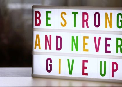 Motivational lightbox sign displaying 'Be Strong and Never Give Up.'
